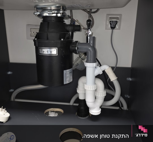 כיור עם צנרת וכלים מתחת לכיור במטבח